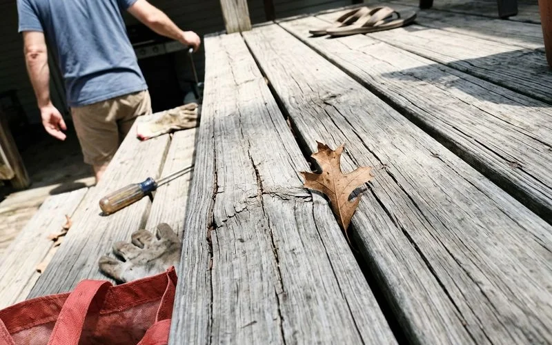 Gray, split deck board surface in harsh sun