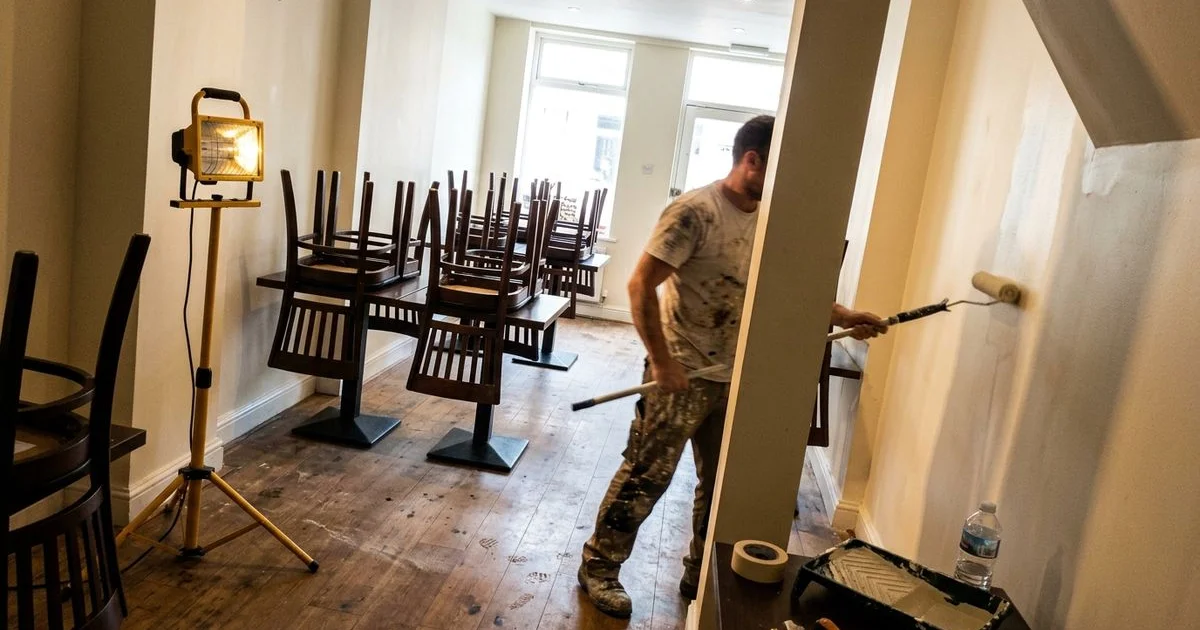 Restaurant dining room after close with chairs stacked on tables and a painter at work