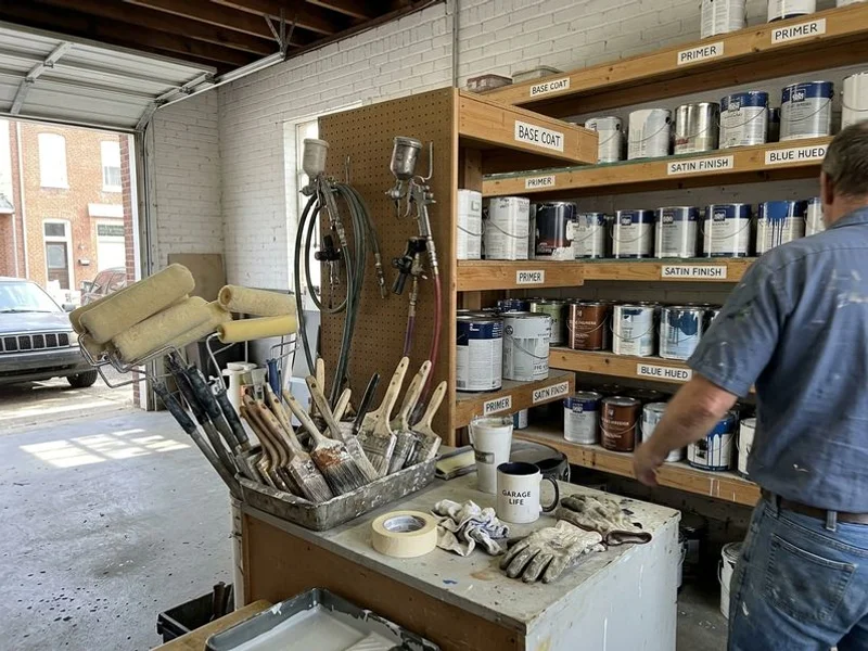 Organized paint shop with labeled cans, rollers and spray equipment