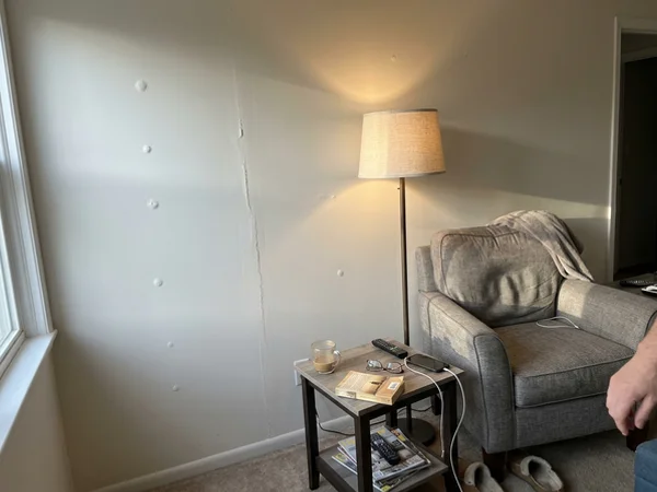 Before: living room wall with nail pops and a cracked tape joint