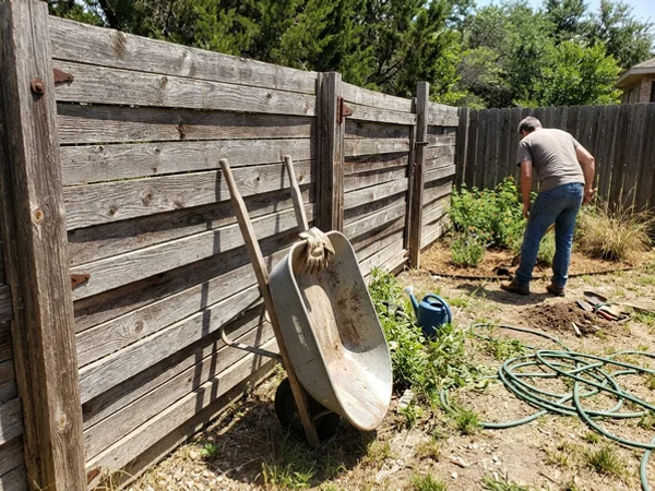 Before: sun-grayed cedar fence with weathered boards