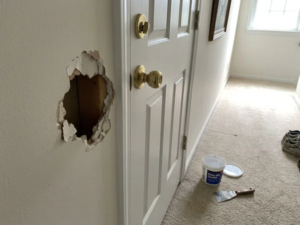 Fist-size hole in hallway drywall before repair