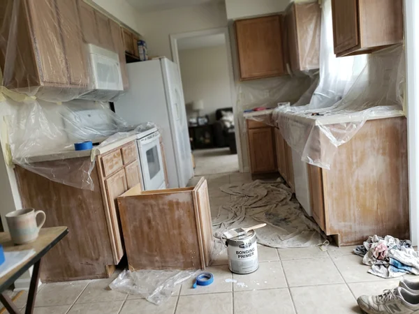 Kitchen masked in plastic with cabinet boxes ready for primer