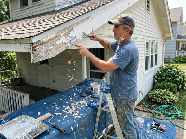 Scraping peeling paint from fascia before priming